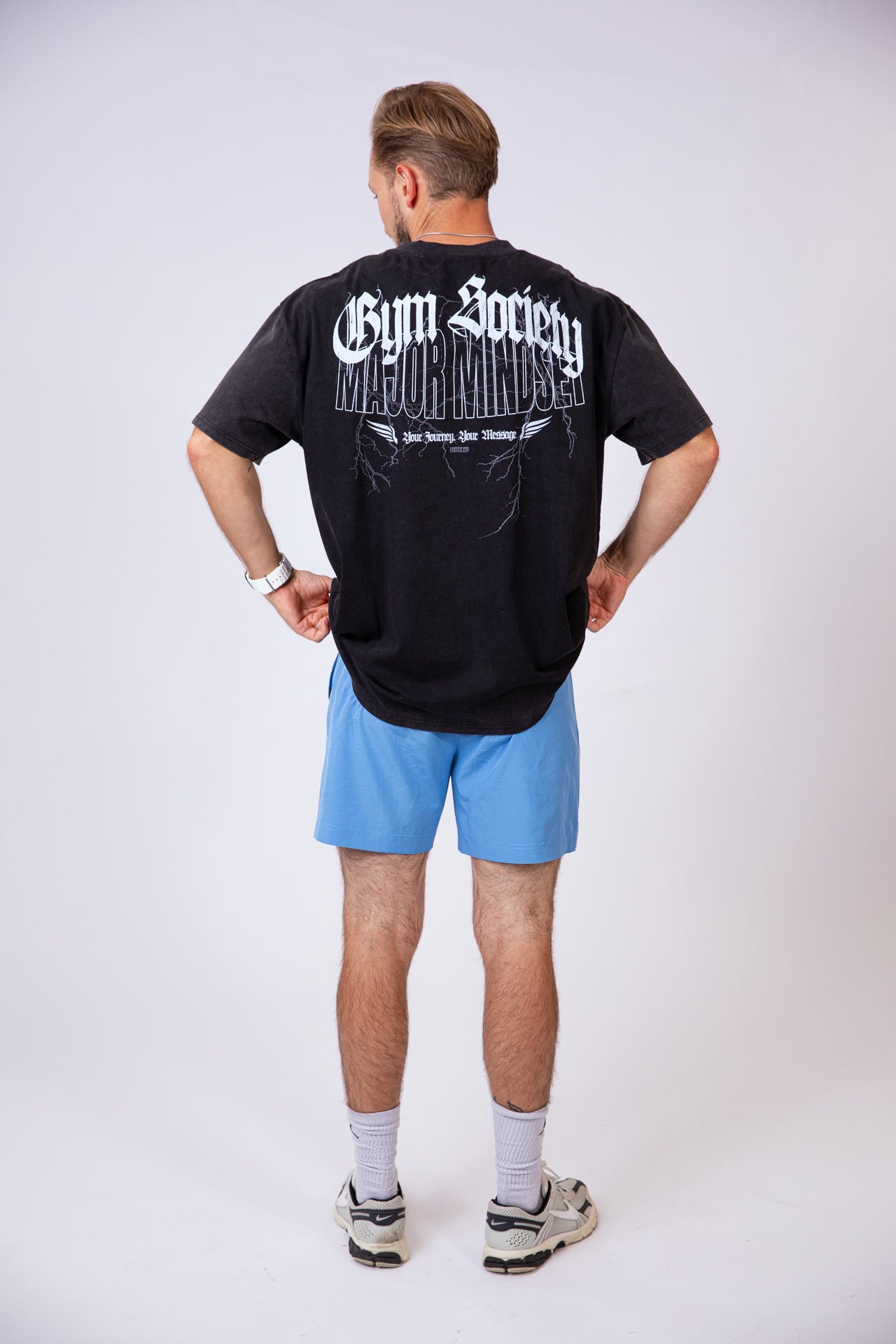 Oversized T-Shirt im Washed Look von hinten mit Gothic Backprint. Model zieht Shirt leicht hoch.